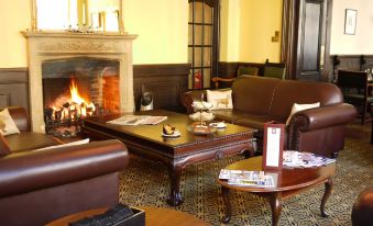 a cozy living room with leather couches and chairs arranged around a fireplace , creating a warm and inviting atmosphere at The Snooty Fox