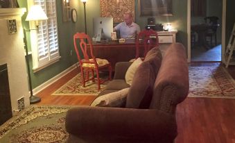 a man is sitting at a desk in a living room with a couch and fireplace at Fiddler's Inn