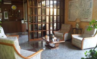 a living room with wooden furniture , including a couch , chairs , and a coffee table , surrounded by a glass wall at Hotel Sole