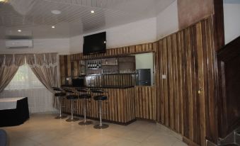 a bar area with wooden walls , a tv mounted on the wall , and several stools arranged around the counter at Occasions