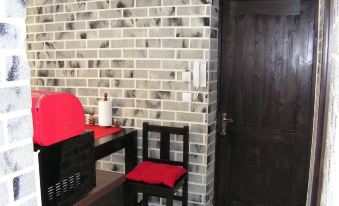 a room with a brick wall , black doors , and a red chair next to a desk at Studio London