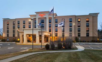 a large hotel with a beige exterior and multiple flags flying in front of it at Hampton Inn Warrenton, VA