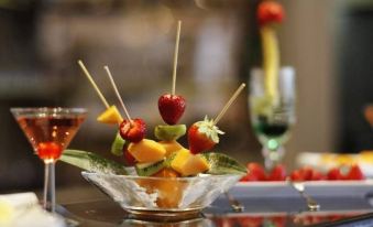 a bowl filled with a variety of fresh fruits , including strawberries , kiwis , and mangoes , placed on a dining table at Hampton by Hilton Rome North Fiano Romano