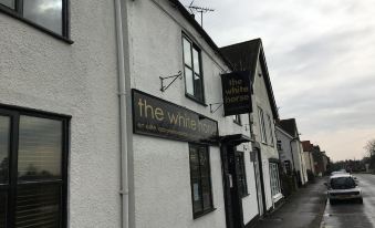 "a white building with a sign that reads "" the white "" on it , located in a small town" at The White Horse
