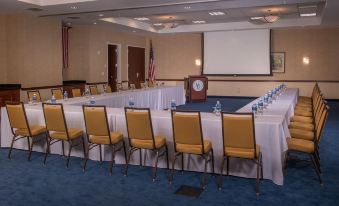 a conference room set up for a meeting , with chairs arranged in a semicircle around a table and a projector screen on the wall at Courtyard Newark-University of Delaware