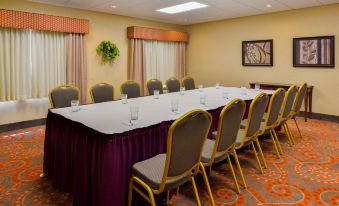 a conference room with a long table , chairs , and two large windows is set up for a meeting at Homewood Suites by Hilton Dover