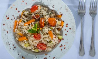 a white plate filled with a variety of vegetables , including carrots , tomatoes , and broccoli , accompanied by a fork at Naxos Palace Hotel