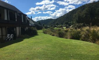 a lush green field with a house in the background and mountains in the background at Alpine Lodge