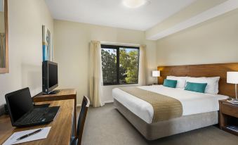 a hotel room with a comfortable bed , a desk , and a tv , all in a modern style at Quest Bendigo Central