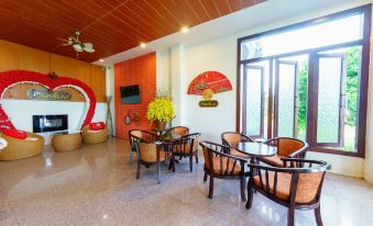 a modern living room with wooden furniture , large windows , and a tv , decorated with red fans and yellow flowers at Vieng Khong Hotel