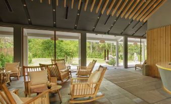 a modern , minimalist room with wooden beams and large windows , featuring a variety of comfortable seating options such as rocking chairs and couches at Alba Wellness Resort by Fusion