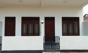 a white building with brown doors and windows , a blue sign on the side , and a black railing on the sidewalk at Sea Breeze