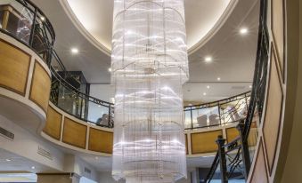 a large , modern chandelier hanging from the ceiling of a spacious room with multiple floors and balconies at Carlton Hotel