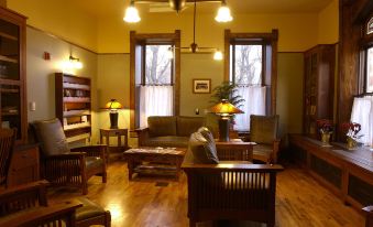 a cozy living room with wooden floors , large windows , and various furniture , including couches , chairs , and tables at Midland Railroad Hotel