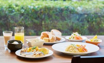 a dining table with a variety of food items , including sandwiches , pasta , and a glass of juice at Mitsui Garden Hotel Okayama