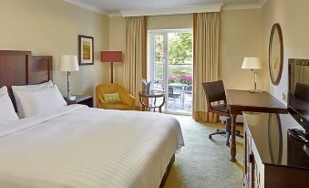 a hotel room with a large bed , a chair , and a sliding glass door leading to a patio at Delta Hotels Tudor Park Country Club