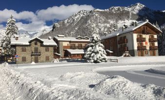 a snowy mountain village with a large building and a tree in the foreground , surrounded by snow at Hotel Lo Scoiattolo