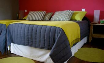 a bed with a gray and yellow blanket and three striped pillows is shown in a bedroom at Punto y Aparte