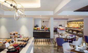 a modern , well - lit dining area with a large dining table and chairs , as well as various food items on display at Le Méridien Goa, Calangute