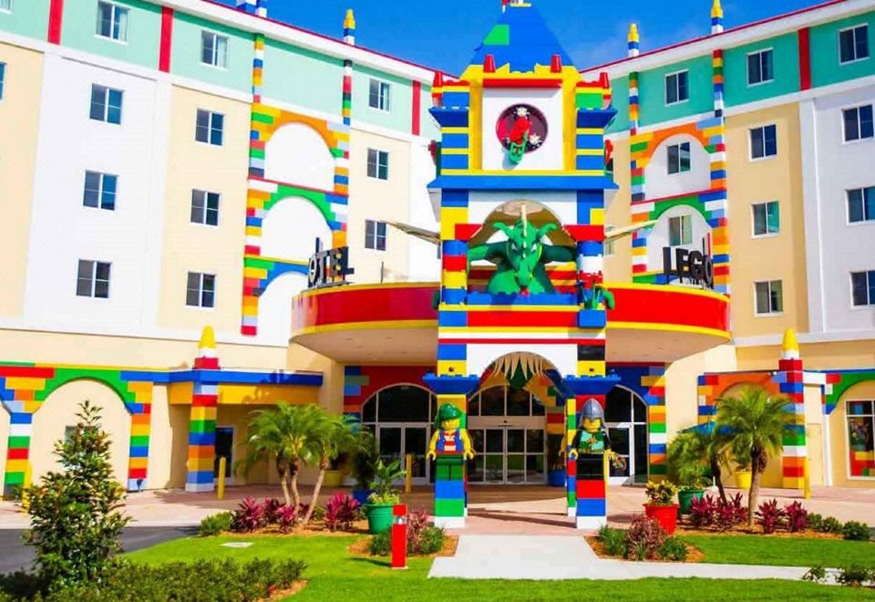 a colorful building with a clock on the side , surrounded by grass and trees , and decorated with lego bricks at Legoland® Florida Resort