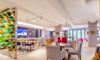 a restaurant with tables and chairs in the center, as well as other seating areas for customers at Campanile Hotel (Shanghai Railway Station, People's Square)