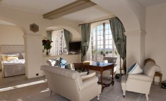 a spacious living room with white walls , large windows , and beige furniture , including a couch , chairs , and a coffee table at Château le Cagnard