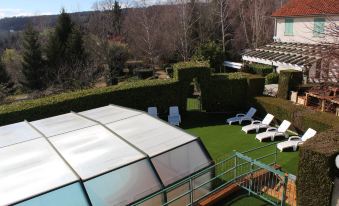 a large white tent set up on a grassy field , surrounded by trees and mountains in the background at Auberge la Tomette, the Originals Relais