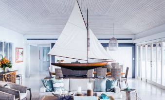 a large white sailboat hangs from the ceiling in a room with a couch and table at Kokomo Private Island Fiji