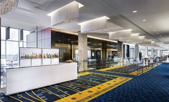 a large hotel lobby with blue and yellow carpet , a white reception desk , and several chairs at Montreal Airport Marriott in-Terminal Hotel