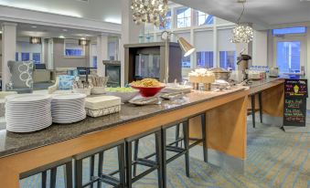 a well - lit dining area with a long wooden table and several chairs , filled with various food items and utensils at Residence Inn Richmond Chester