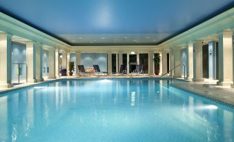 an indoor swimming pool surrounded by chairs and a building with large windows , creating a serene atmosphere at Cbh Hythe Imperial Hotel Golf and Spa