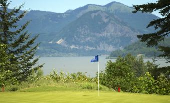 a scenic view of a golf course with a flag and mountains in the background at Skamania Lodge