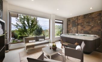 a modern living room with large windows , stone walls , and a hot tub situated on a balcony at Koanze Luxury Hotel & Spa