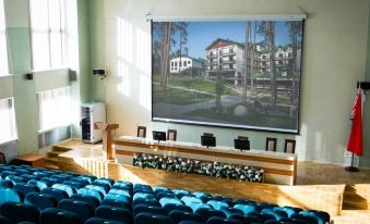 a large room with a screen displaying an image of a building and chairs in front of it at Forum
