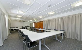 a large conference room with multiple white tables and chairs arranged in rows , creating an event space at Prince of Wales Hotel
