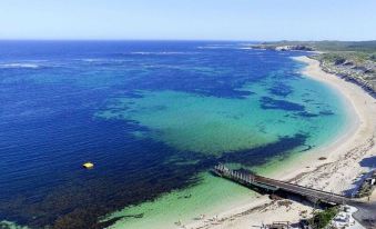 a beautiful beach scene with clear blue water , white sand , and a yellow boat floating in the ocean at Margarets Beach Resort