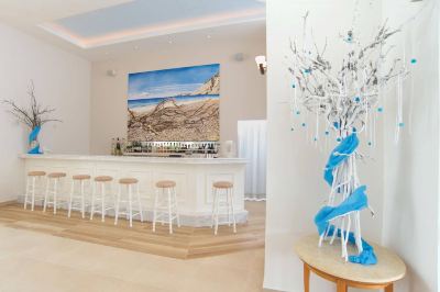 a modern bar with white stools , a painting on the wall , and a blue sculpture of a tree at Hotel Summery