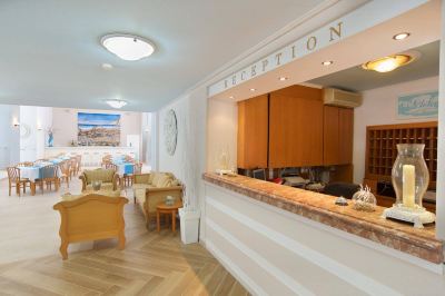 a reception area with a desk , chairs , and a clock on the wall , along with some furniture at Hotel Summery