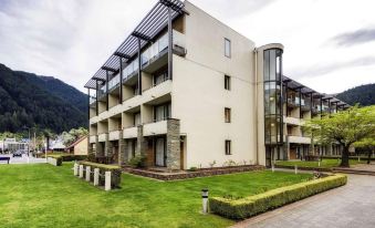 a large , modern apartment building with multiple balconies and a grassy yard in front at Novotel Queenstown Lakeside