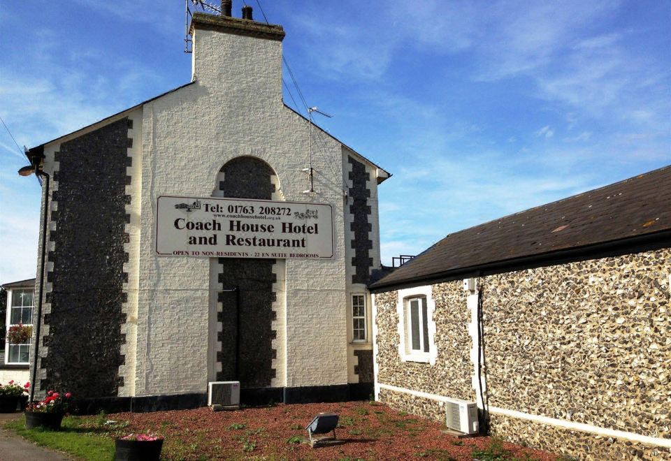 "a brick building with a sign that reads "" the barn "" and "" coach house hotel ""." at Coach House Hotel