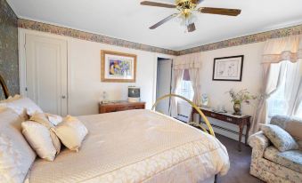 a cozy bedroom with a large bed , a desk , and a ceiling fan , decorated with pictures and artwork on the walls at Maple Springs Lake Side Inn