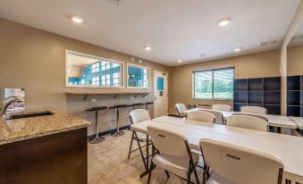 a well - lit dining room with a long table and chairs , a bar area , and large windows at Comfort Inn & Suites