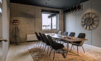 a large conference room with a long wooden table surrounded by chairs , and a clock on the wall at Moxy Edinburgh Airport