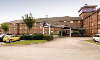 an exterior view of a hotel with a large sign above the entrance , surrounded by trees at Premier Inn Derby East