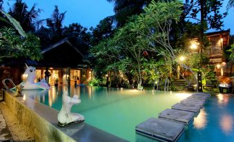 a large swimming pool surrounded by lush greenery , with several people enjoying their time in the pool at Astuti Gallery Homestay