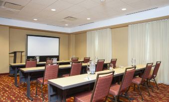 a conference room with chairs arranged in rows and a projector screen on the wall at Courtyard Peoria Downtown