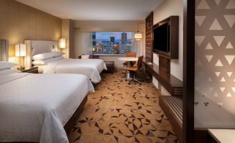 a hotel room with two beds , a desk , and a window overlooking a cityscape at night at Sheraton Grand Seattle