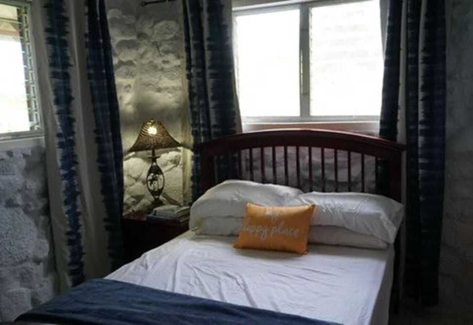 "a bed with a white sheet and a pillow that says "" stay alive "" is situated next to a window" at Casa Piedra