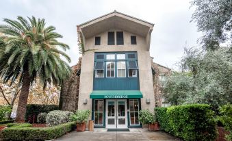 a modern building with a green awning and potted plants in front , under an overcast sky at Southbridge Napa Valley