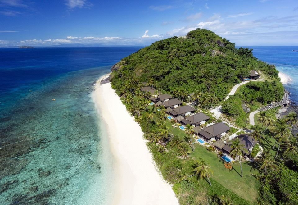 aerial view of a tropical island with white sand beach , lush green vegetation , and a beach resort at Matamanoa Island Resort